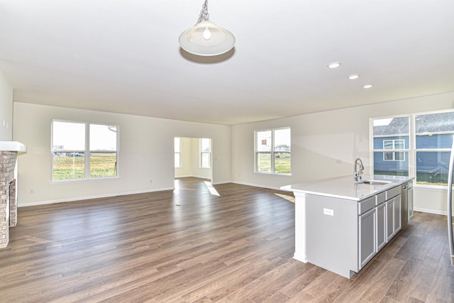 kitchen featuring open floor plan, a sink, a stone fireplace, and wood finished floors