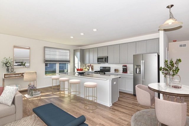 kitchen featuring visible vents, a kitchen breakfast bar, stainless steel appliances, gray cabinetry, and light wood-style floors