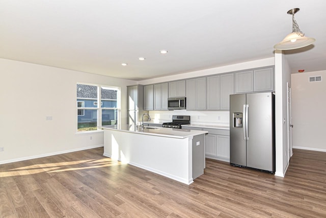 kitchen featuring stainless steel appliances, visible vents, gray cabinetry, a sink, and wood finished floors