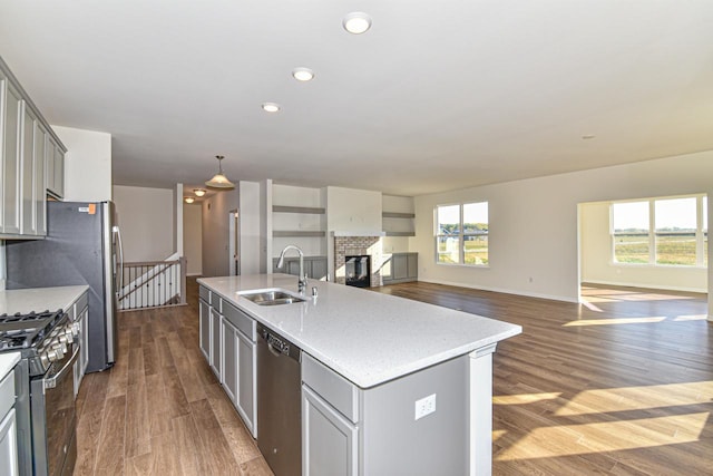 kitchen featuring stainless steel appliances, gray cabinets, a sink, and dark wood finished floors