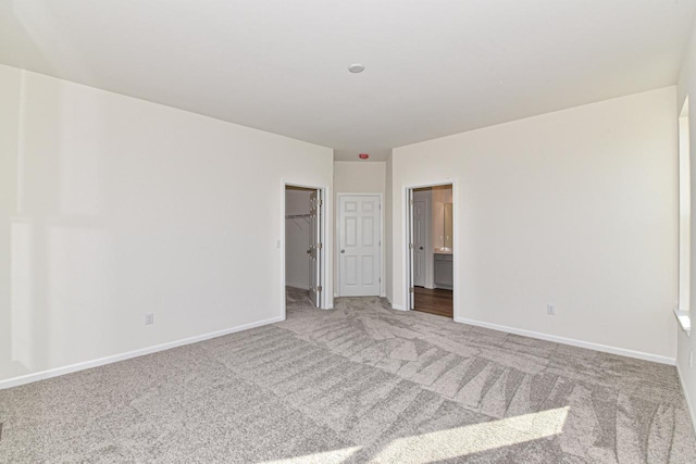 spare room featuring light colored carpet and baseboards