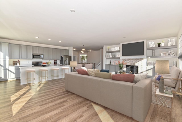 living area with light wood-type flooring, a fireplace, and recessed lighting