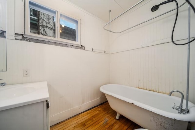 full bath featuring hardwood / wood-style flooring, a soaking tub, vanity, and crown molding