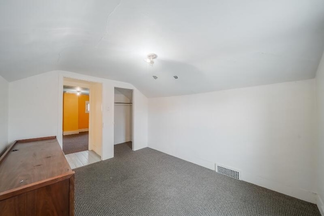 additional living space featuring visible vents, vaulted ceiling, and carpet flooring