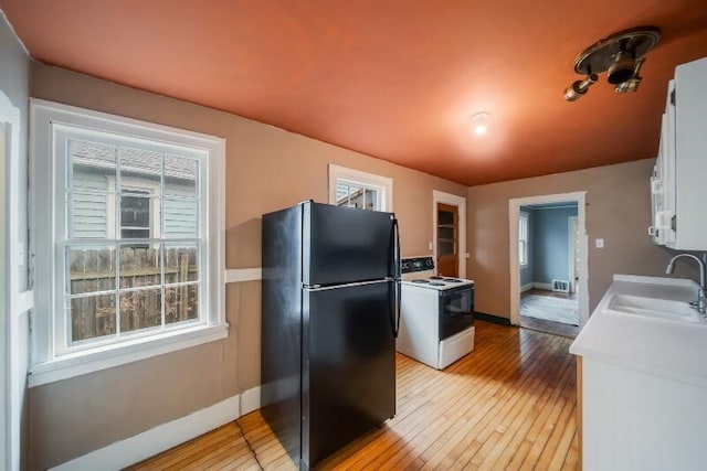 kitchen with light countertops, electric range, freestanding refrigerator, white cabinets, and a sink