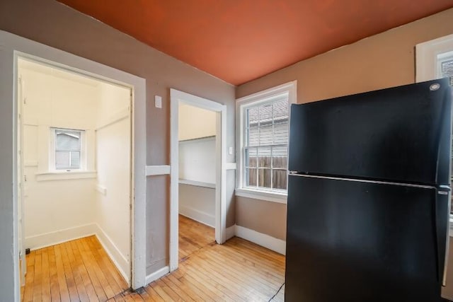 interior space with light wood finished floors, freestanding refrigerator, and baseboards