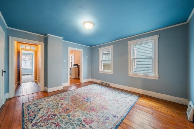 bedroom with washer / clothes dryer, visible vents, baseboards, hardwood / wood-style floors, and crown molding