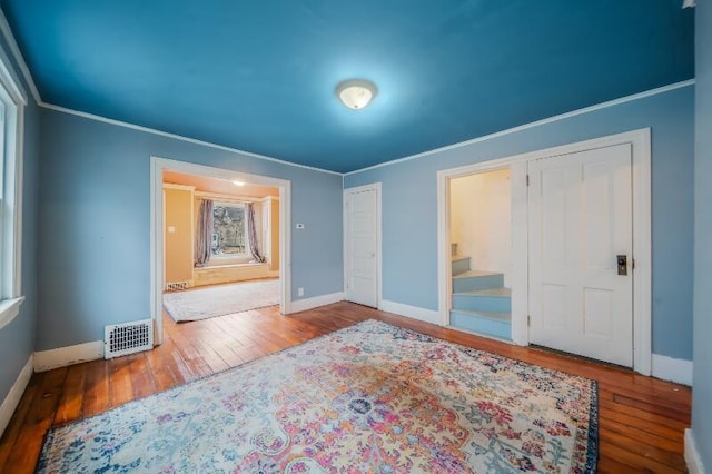 bedroom featuring visible vents, crown molding, and wood finished floors