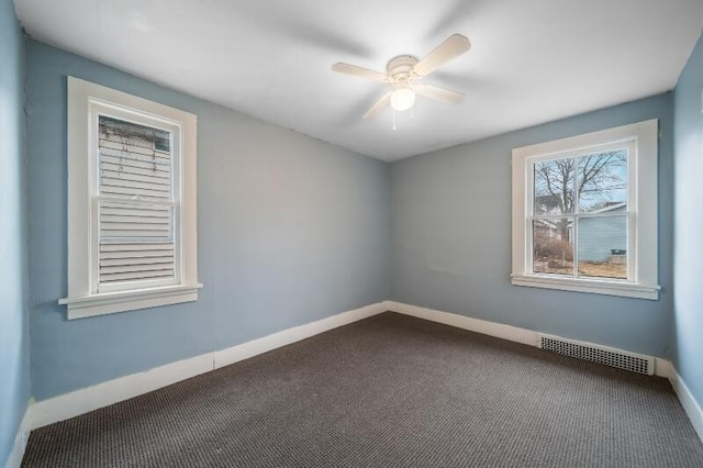 unfurnished room with baseboards, visible vents, dark colored carpet, and a ceiling fan