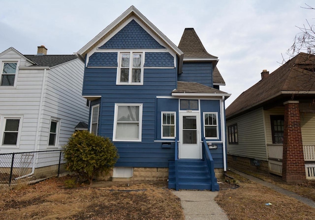 view of front facade featuring entry steps, fence, and roof with shingles