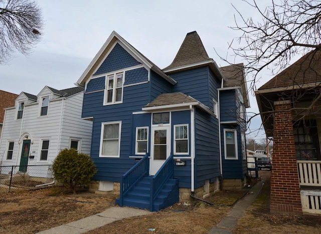 view of front of home featuring entry steps, a shingled roof, and fence