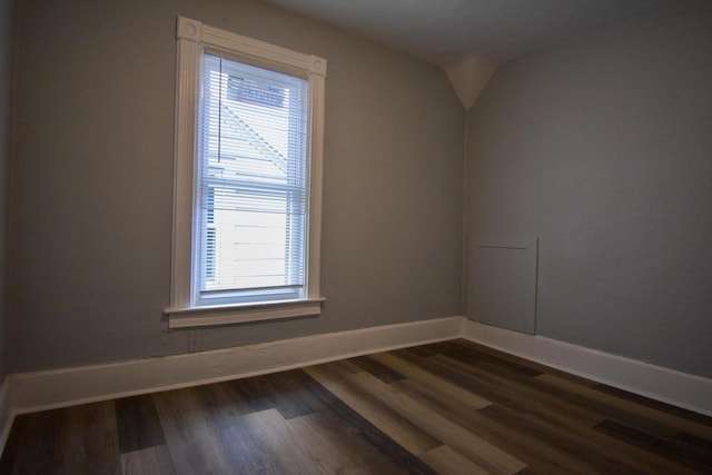 spare room featuring dark wood-style floors and baseboards