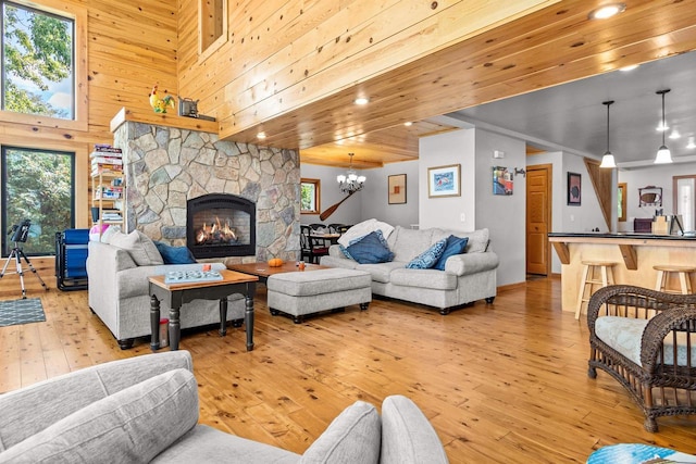 W3084 Blackbird Point Dr, Green Lake, WI 53946 - living area with light wood-style floors, healthy amount of natural light, a chandelier, a stone fireplace, and wooden walls