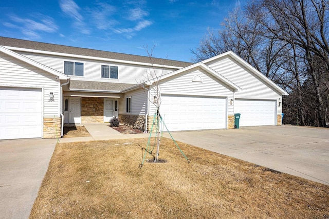 view of front of property with stone siding, concrete driveway, roof with shingles, and a garage