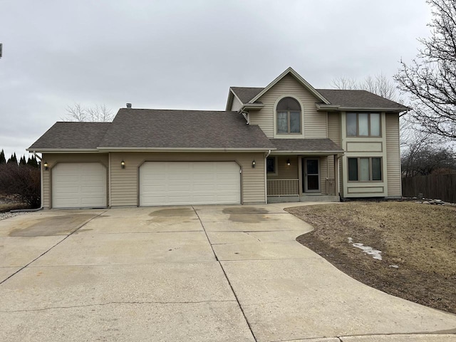 traditional home featuring concrete driveway, roof with shingles, and an attached garage