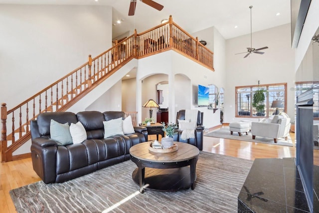 living area featuring stairway, baseboards, ceiling fan, and hardwood / wood-style floors