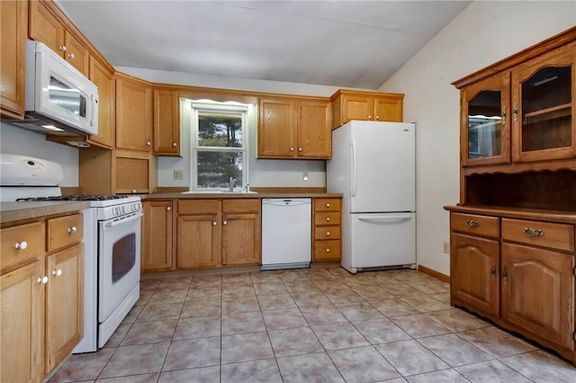 kitchen with vaulted ceiling, white appliances, light tile patterned flooring, and a sink