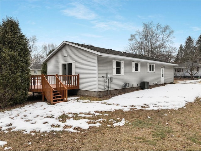 snow covered house featuring central AC unit and a wooden deck