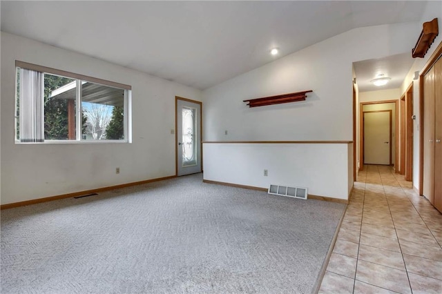 empty room with vaulted ceiling, visible vents, and light colored carpet