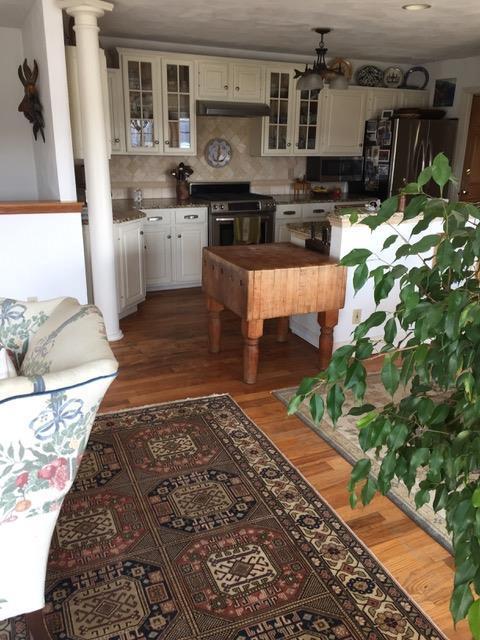 kitchen featuring under cabinet range hood, wood finished floors, gas range oven, fridge, and ornate columns