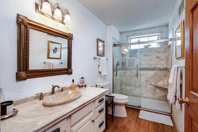 full bathroom featuring visible vents, toilet, wood finished floors, and a shower stall