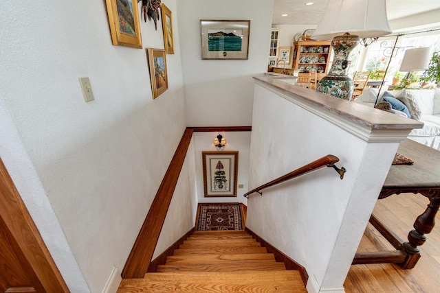 stairway with recessed lighting, baseboards, and wood finished floors