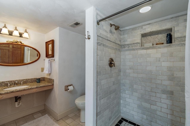 full bath featuring baseboards, visible vents, tiled shower, a sink, and toilet