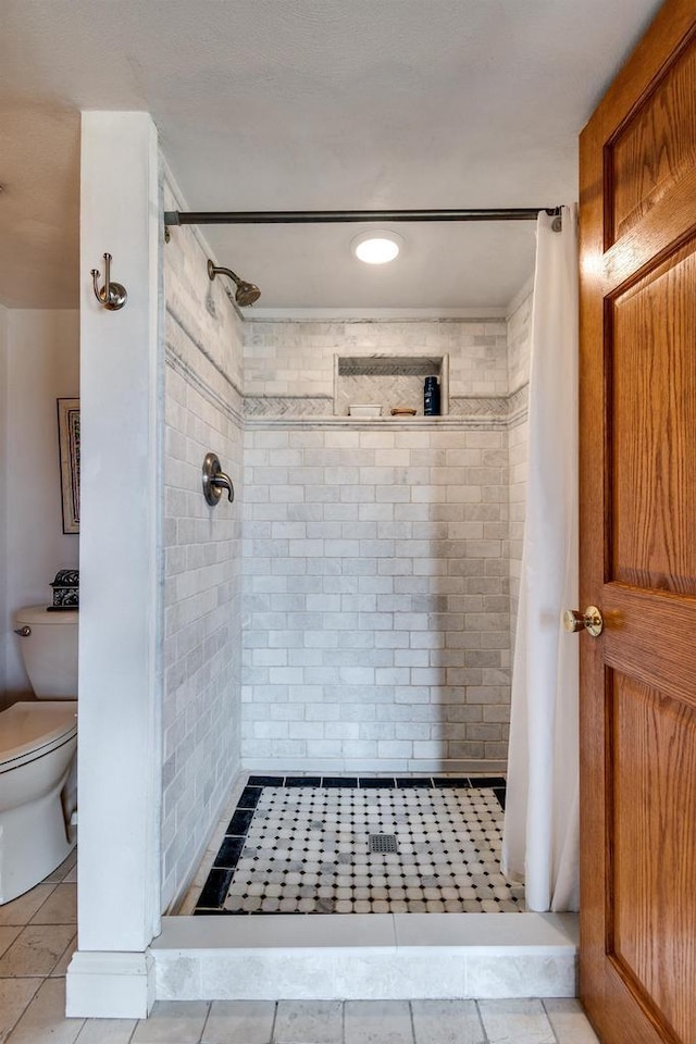 bathroom with tile patterned floors, toilet, and a shower stall