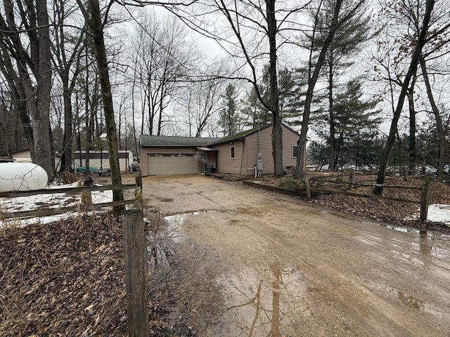 view of front of property featuring an attached garage and dirt driveway