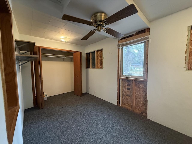 unfurnished bedroom with dark colored carpet, a closet, and ceiling fan