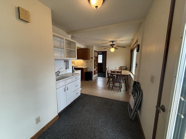 kitchen featuring open shelves, a sink, light countertops, baseboards, and ceiling fan