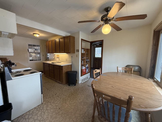 kitchen featuring visible vents, a sink, ceiling fan, light countertops, and white range with electric stovetop