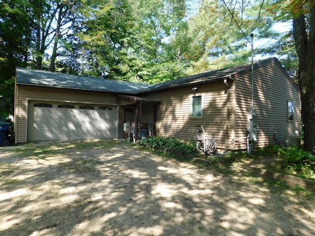 ranch-style home with an attached garage and dirt driveway