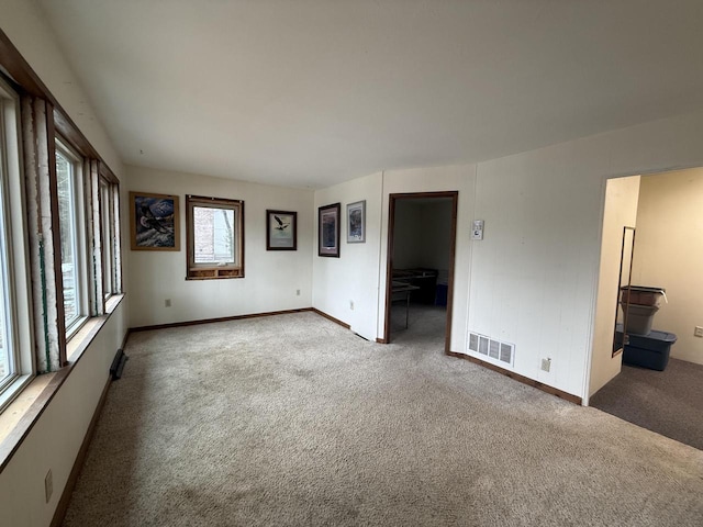 carpeted spare room featuring visible vents and baseboards