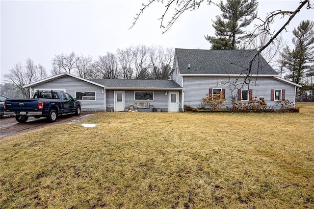 view of front of house with a shingled roof and a front yard