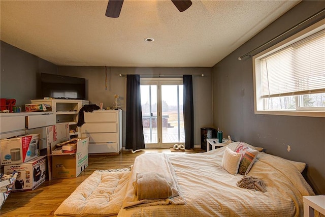 bedroom with a textured ceiling, a ceiling fan, and wood finished floors