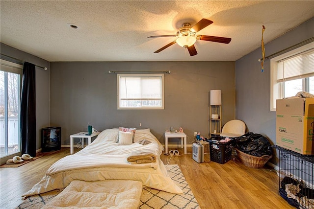 bedroom with a textured ceiling, baseboards, and wood finished floors