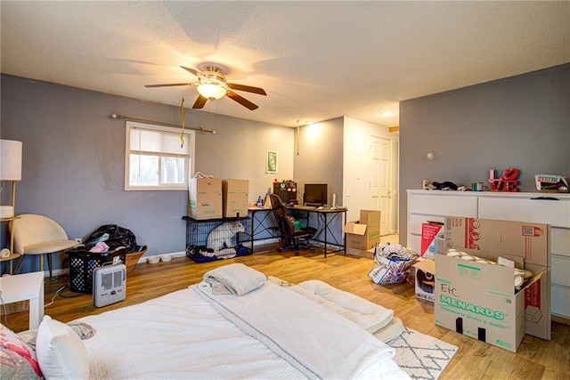 bedroom with ceiling fan, a textured ceiling, baseboards, and wood finished floors