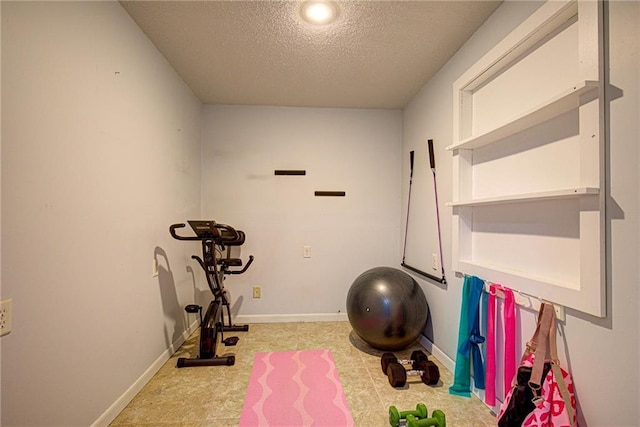 exercise room with a textured ceiling and baseboards