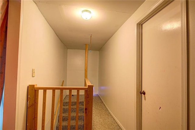 hallway featuring baseboards, carpet flooring, and an upstairs landing