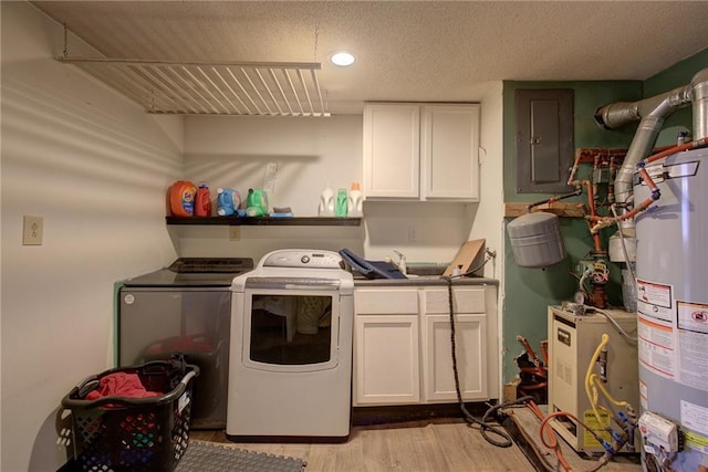 washroom with a textured ceiling, water heater, independent washer and dryer, cabinet space, and electric panel