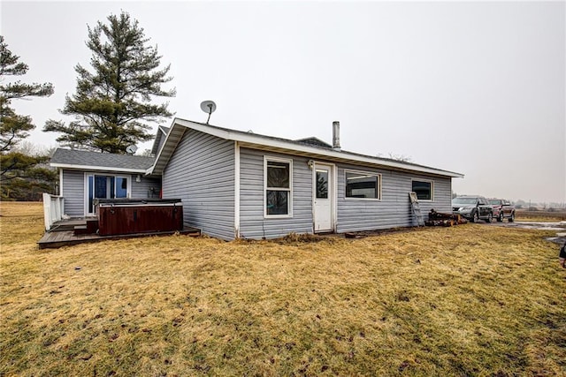 rear view of property with a yard and a hot tub