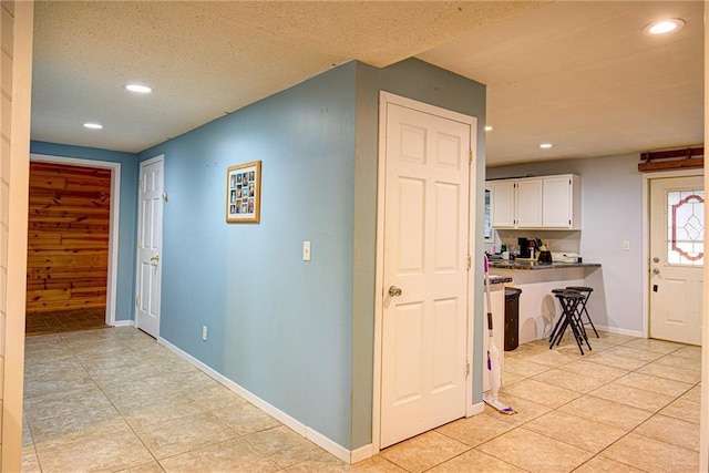 corridor with baseboards, a textured ceiling, and recessed lighting