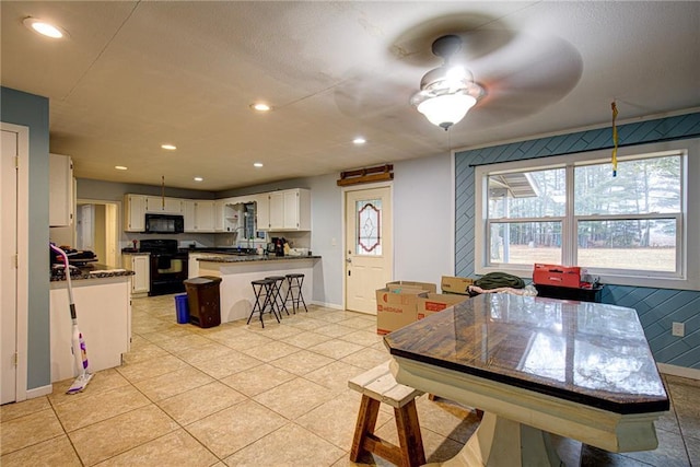 kitchen featuring recessed lighting, a peninsula, white cabinetry, black appliances, and dark countertops