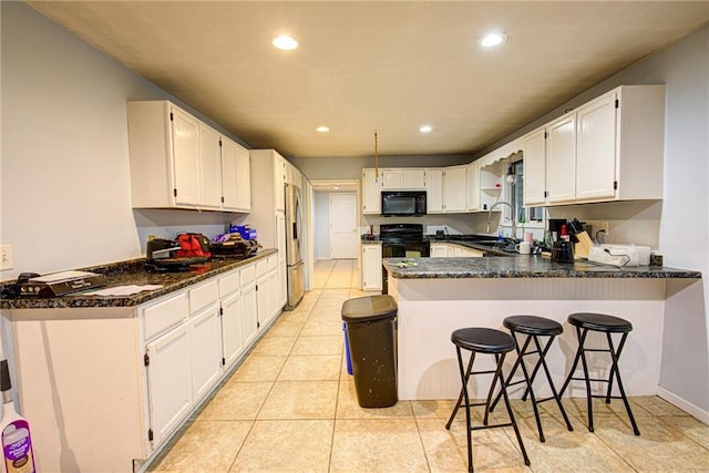 kitchen with black appliances, a peninsula, white cabinetry, and recessed lighting