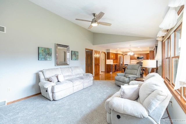 carpeted living area featuring visible vents, vaulted ceiling, baseboards, and ceiling fan with notable chandelier