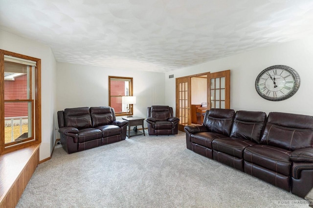 living area featuring a wealth of natural light, french doors, carpet flooring, and a textured ceiling