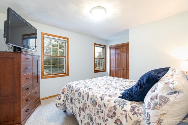 bedroom featuring baseboards, a closet, and light colored carpet