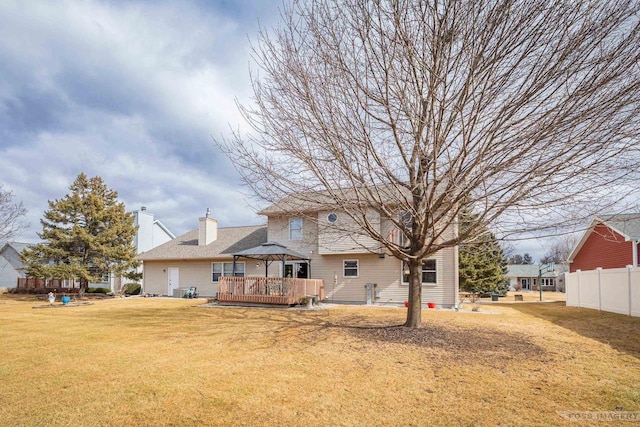 back of house featuring a lawn, a chimney, fence, a deck, and a gazebo