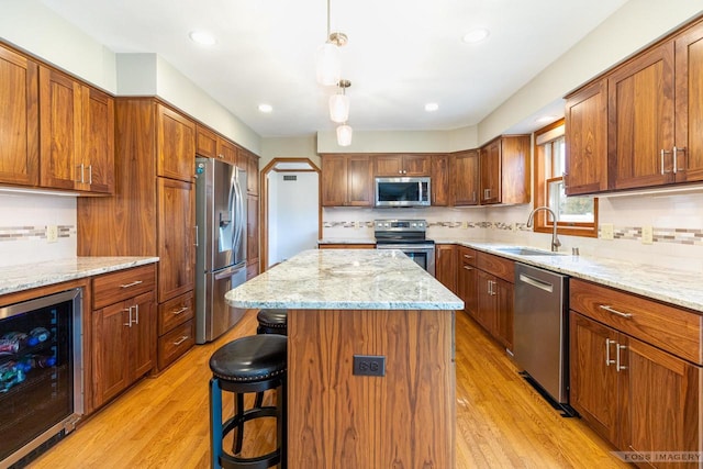 kitchen with appliances with stainless steel finishes, wine cooler, a sink, and light wood-style flooring